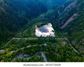 Aerial view of a secluded mountain lake surrounded by lush greenery in a valley, reflecting the sky above - Powered by Shutterstock