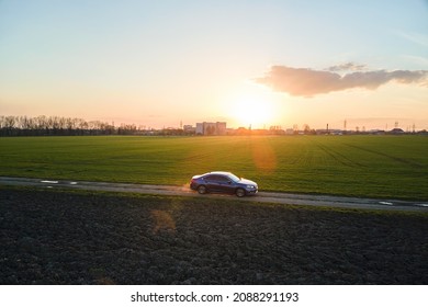 Aerial view of sedan car driving fast on dirt road at sunset. Traveling by vehicle concept.