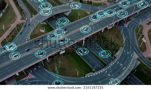 Aerial view: Self-driving autonomous electric cars\
of the future with HUD elements move along a busy traffic\
intersection. Concept: Artificial Intelligence, Car Scan, GPS\
Tracking, Smart Roads,\
IoT.
