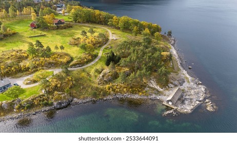 Aerial view of a serene coastal landscape featuring a calm sea, lush green hills, and scattered islands. The scene is adorned with autumn foliage, showcasing vibrant colors against a cloudy sky. - Powered by Shutterstock