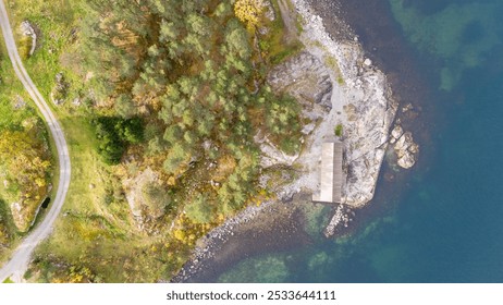 Aerial view of a serene coastal landscape featuring a calm sea, lush green hills, and scattered islands. The scene is adorned with autumn foliage, showcasing vibrant colors against a cloudy sky. - Powered by Shutterstock