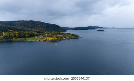 Aerial view of a serene coastal landscape featuring a calm sea, lush green hills, and scattered islands. The scene is adorned with autumn foliage, showcasing vibrant colors against a cloudy sky. - Powered by Shutterstock