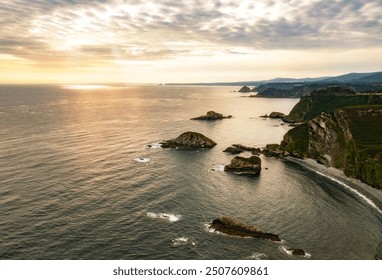 Aerial view of a serene coastline at sunset with calm ocean waves, rocky formations - Powered by Shutterstock