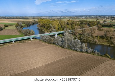 Aerial view of a serene landscape featuring a river, lush trees, and farmland, showcasing the tranquil beauty of nature and agricultural harmony. - Powered by Shutterstock