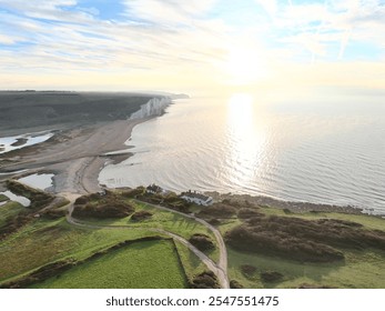 Aerial view of the Seven Sisters cliffs and coastline with lush green fields under a bright sky in East Sussex, England. - Powered by Shutterstock