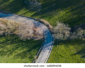 Aerial View Of Sharp Hairpin Curve Of Road Through Green Meadow. Concept Of Traveling By Car.