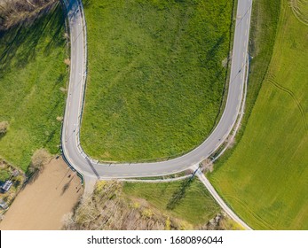 Aerial View Of Sharp Hairpin Curve Of Road Through Green Meadow. Concept Of Traveling By Car.