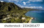 An aerial view of the shore in Kaneohe, Hawaii with a planet in the cloudy sky in the background