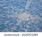 An aerial view shows the town of Cerignola, Italy, with its buildings arranged in a radial pattern surrounded by agricultural fields.