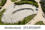 Aerial view of a skateboarding playground in a city park. There are no children and the playground is empty.