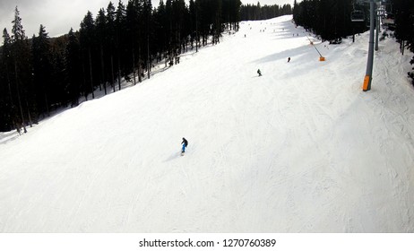 Aerial view of skiers and snowboarders on ski slope on sunny day