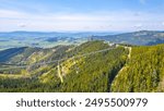 Aerial view of the Sky Bridge 721, the worlds longest suspension footbridge, stretching across a forested mountain in Czechia. The unique Sky Walk lookout tower stands nearby, offering panoramic views