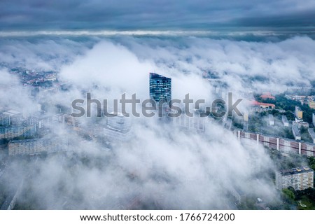 Aerial view of skyscraper Sky Tower in the fog in Wroclaw. Epic foggy morning in the city and tall building in the clouds. Wroclaw, Poland