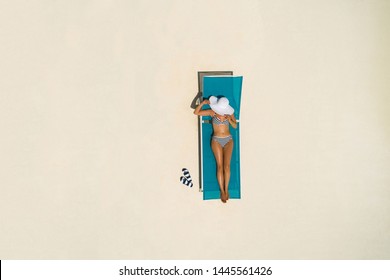 Aerial view of slim woman sunbathing lying on a beach chair in Maldives. Summer seascape with girl. Top view from drone.