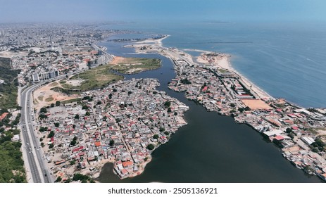 Aerial view of the slums in Luanda, Angola, showcasing urban housing along the water and surrounding landscapes - Powered by Shutterstock