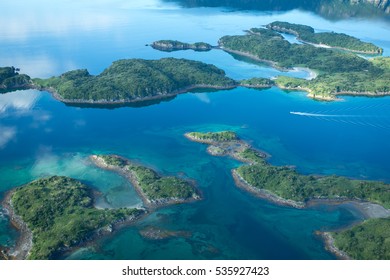 aerial view of small alaskan islands near kodiak alaska with emerald green vegetation and fishing boat in the channel 
