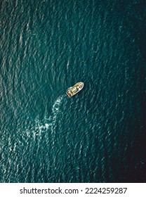 An Aerial View Of A Small Boat In Dark Green Sea Water