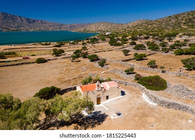 Aerial View Of A Small Church Next To A Blue Ocean On A Hot Greek Island (Ascension Church, Elounda, Crete)