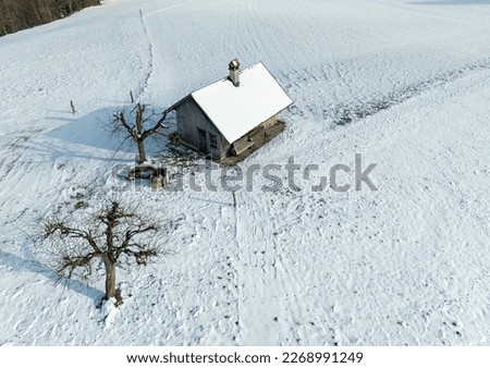 Aerial view of a small cottage in a snow covered rural landscape in winter time.