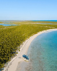 Aerial View Of Small Illegal Ship Abandoned On Vast Undeveloped Coast Of Caribbean Island Filled With Trees, Swamps And A Clear Sky