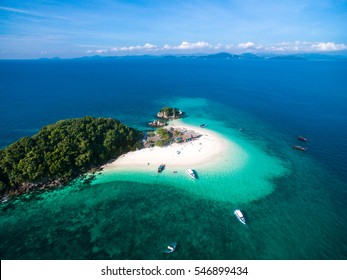 Aerial view of small isolated tropical island with white sandy beach and blue transparent water and coral reefs. Top view, speedboats, longtail boats, Khai Nok island, Phuket, Thailand.