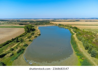 Aerial view of a small reservoir in a field. A lake for fishing in Sisterea - Romania. Solution against the drought in agriculture for irrigation - Shutterstock ID 2368683147