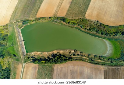 Aerial view of a small reservoir in a field. A lake for fishing in Sisterea - Romania. Solution against the drought in agriculture for irrigation - Shutterstock ID 2368683149