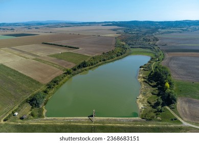 Aerial view of a small reservoir in a field. A lake for fishing in Sisterea - Romania. Solution against the drought in agriculture for irrigation - Shutterstock ID 2368683151