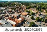 Aerial view of a small town featuring a mix of residential and commercial buildings, green trees, and open fields in the background. Ripon, North Yorkshire, UK.