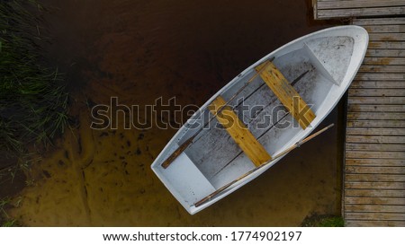 Aerial view of a small white boat floating on the lake near the pier