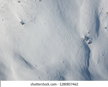 Aerial view of snow covered mountain with impressive structure. White surface of wild mountain from above in top view. Snow texture in wilderness. - Powered by Shutterstock