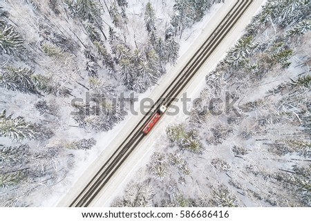 Aerial view of snow covered road in winter forest, truck passing by, motion blur