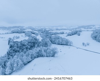 Aerial view of snow covered rural countryside in Switzerland, Europe. Trees and houses in winter time.