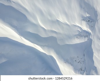 Aerial View Of Snow Covered Terrain In Mountain Area. Mountains In Central Switzerland. Alps With Snow In Beautiful Light With Shadow And Sun.