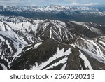 Aerial view of the snow-covered mountains in the Magadan region of Russia. Winter landscape of the mountains. Air travel to the far north of Russia. Nature of Siberia and Russian Far East