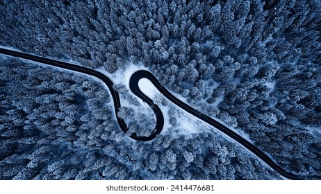 Aerial view of snowy forest with amazing curved road. Top photo taken with a drone.	

