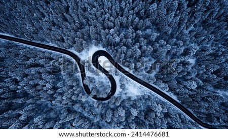 Aerial view of snowy forest with amazing curved road. Top photo taken with a drone.	
