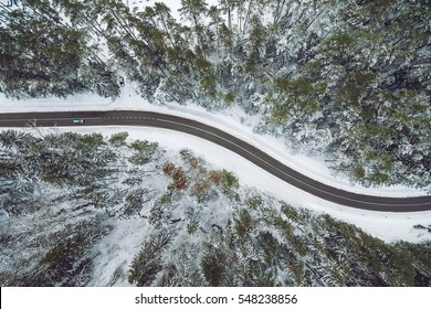 Aerial view of snowy forest with a road. Captured from above with a drone
