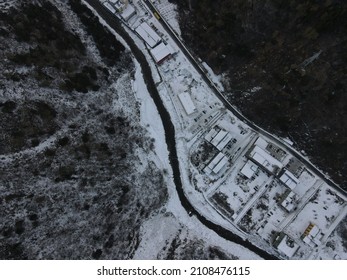 An Aerial View Of Snowy Road Between Range Of Mountains Against A Light Blue Sky Rogers Pass, Canada