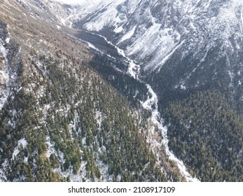 An Aerial View Of Snowy Road Between A Range Of Mountains Against A Light Blue Sky Rogers Pass, Canada