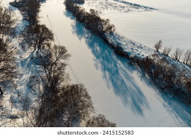 Aerial view of a snowy winter river with a lone skier in the distance - Powered by Shutterstock