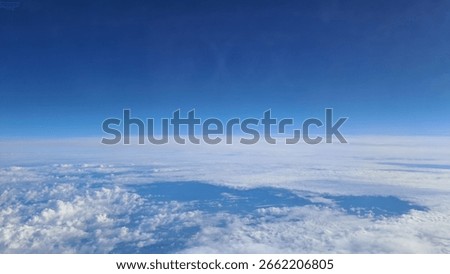 Aerial view of soft cloud layers seen from high flying commercial airplane window.