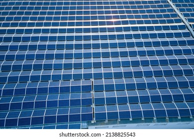 Aerial view of solar power plant with blue photovoltaic panels mounted on industrial building roof for producing green ecological electricity. Production of sustainable energy concept - Shutterstock ID 2138825543