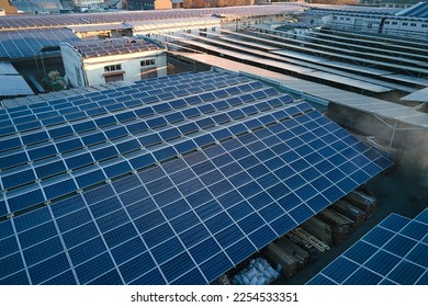 Aerial view of solar power plant with blue photovoltaic panels mounted on industrial building roof for producing green ecological electricity. Production of sustainable energy concept - Shutterstock ID 2254533351