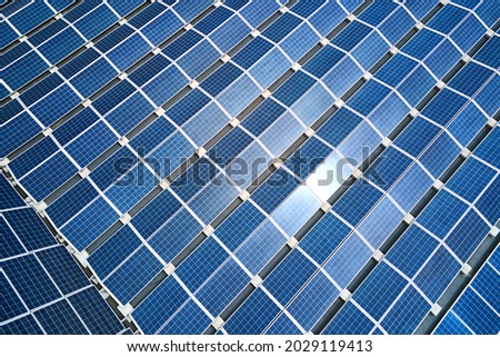 Aerial view of solar power plant with blue photovoltaic panels mounted on industrial building roof for producing green ecological electricity. Production of sustainable energy concept.