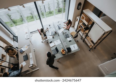 An aerial view of a spacious, well-lit office with diverse employees engaged in their tasks at individual desks and collaborating. - Powered by Shutterstock