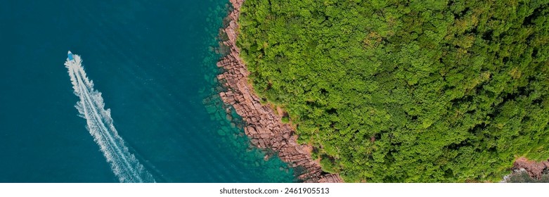 Aerial view of a speedboat cruising along the coast with lush greenery and rocky shoreline, ideal for summer vacation and adventure travel themes - Powered by Shutterstock