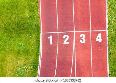 Aerial view of sports stadium with red running tracks with numbers on it and green grass football field. - Shutterstock ID 1883338762