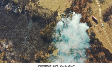 Aerial View. Spring Dry Grass Burns During Drought Hot Weather. Bush Fire And Smoke. Fire Engine, Fire Truck On Firefighting Operation. Wild Open Fire Destroys Grass. Ecological Problem Air Pollution.