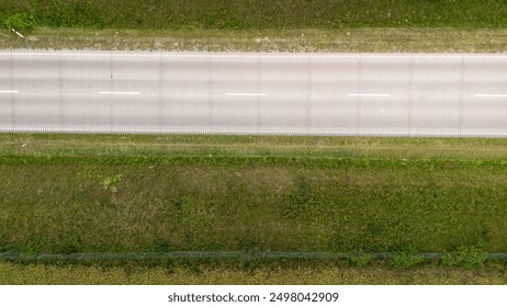 Aerial View of a Straight Rural Road Surrounded by Green Grass and Vegetation - Powered by Shutterstock